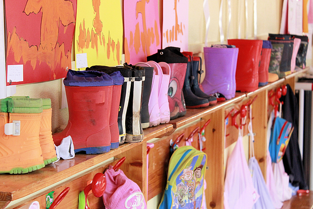 Foto: Bunte Gummistiefel und Rucksäcke in einer Kindergartengarderobe